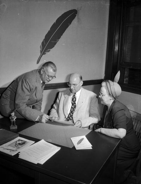 Three Madison citizens involved in directing the United Givers' Fund drive of 1950, the first Madison United Givers' Fund campaign, gather at a desk. Shown from left to right are: Alan C.  Hackworthy, associate chairman of the drive; Oscar Gustave Mayer, chairmen of the drive; and Mrs. Marshall (Vera) Browne, chairperson of the women's division.