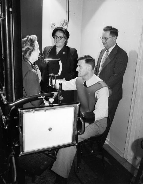 Dr. Chester Kurtz, seated, and Dr. Robin Allin, standing, demonstrate the operation of a fluoroscope to Mrs. David (Virginia) Piper, seated, and Mrs. Joseph (Mary) Barber.  Mrs. Piper and Mrs. Barber are two of the 850 women solicitors of the Madison United Givers' Fund drive of 1950. Drs. Kurtz and Allin are members of the Board of Directors of the Wisconsin Heart Association, which is taking part in the United Givers' Fund drive in Madison.