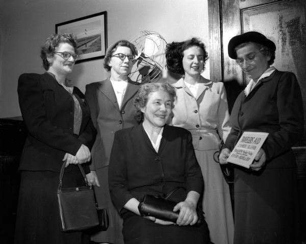Mrs. Sophia Siebecker, far right, explains the duties of the Travelers' Aid Association of which she is the director in Madison, to four United Givers' Fund solicitors. The solicitors are, from left: Mrs. Thomas A. (Jane) Webster, Mrs. Curtis Jensen, Mrs. Mae Diesen (seated), and Mrs. Robert Beberstein. The Travelers' Aid Association is one of the agencies participating in the first United Givers' Fund drive.