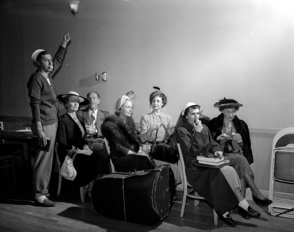 Participants in a skit called "Shorewood Goes to Town" depict a scene on a crowded Shorewood Hills bus at the Shorewood Community League "Shindig" event. From left to right: W.R. Marling, Mrs. M.R. (Margaret) Irwin, O.W Rewey, Mrs. Don (Faye) Nelson, Mrs. Herman (Mildred) Wirka, Mrs. W.R. (Elizabeth) Marling, and Mrs. Ralph E. (Katherine) Axley.