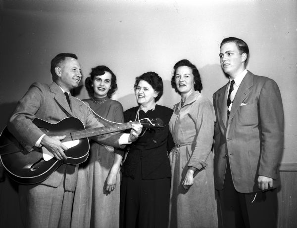 Members of a chorus made up of Shorewood Hills residents and organized by Dr. Edward Gordon rehearse before entertaining guests at the Shorewood Community League "Shindig." Left to right: Dr. Gordon with his guitar, Mrs. Herbert (Patricia) Granger, Mrs. Howard (Mary) Hall, Mrs. James (Betty Geisler), and Hugh Hall.