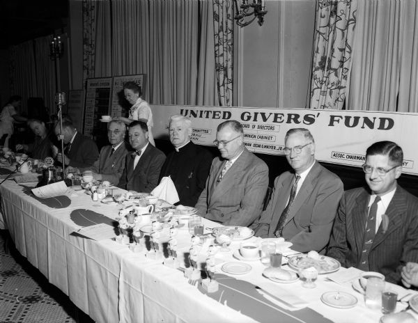 Shown at the United Givers' Fund campaign luncheon speakers' table are, from left to right, starting at sixth from the right: Former Chief Justice Marvin B. Rosenberry of the State Supreme Court, luncheon speaker; Bernhard Mautz, fund president; the Rt. Rev. Msgr. William Mahony, who delivered the invocation; Alan C. Hackworthy, assistant campaign chairman; Dean John Guy Fowlkes, chairman of the campaign's governmental division; and Stanley V. Kubly, campaign area-business division chairman.