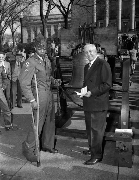 Corporal Albert Griffin, a soldier from Milwaukee wounded in the Korean War, standing with Governor Rennebohm at the freedom bell during ceremonies at the Wisconsin State Capitol on United Nations Day.
