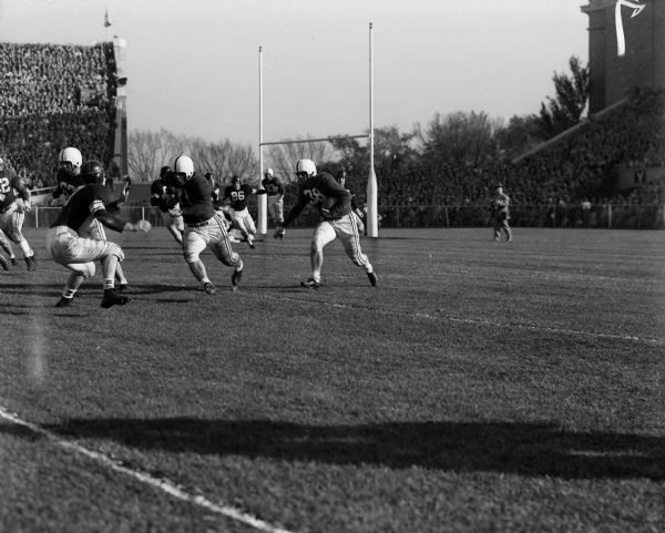 Wisconsin linemen Dave Suminski (#71) and Bob Kennedy (#67) lead the way for fullback Bill Schleisner (#38) who caught a pass from quarterback John Coatta against Northwestern at Camp Randall Stadium.