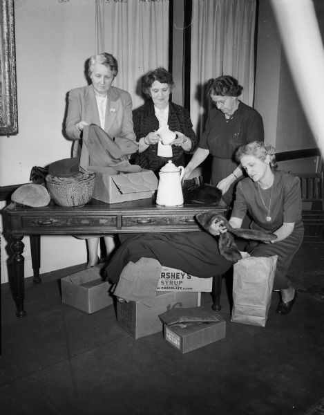 The Zor Shriner Auxiliary's two rummage sales are some of their best fund raising activities, held to benefit the Shriners' hospitals for crippled children. Pictured left to right preparing for the rummage sale are: Mrs. Herbert (Harriet) Loucks, 219 Clifford Street, chairman of the rummage committee, and three of her co-workers: Mrs. W.G. (Pansy) Gerlach, 419 North Murray Street; Mrs. Ben (Anne) Shetney, 914 Swarthmore Court, and Mrs. Herbert H. (Erma) Smith, 2222 Commonwealth Avenue.