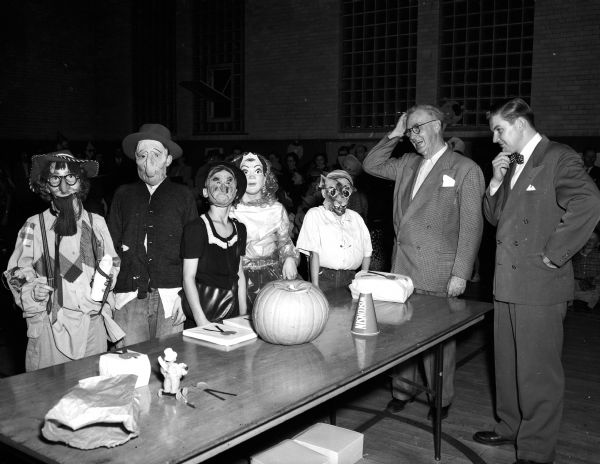 At Lapham School, more than 800 costumed children and their parents attended one of the largest Halloween night parties held in Madison. Judges Roundy, and "Uncle Dick" of radio station WIBA, are shown (at right) puzzling over which of the Lapham School pupils in the garb of goblins and witches should be awarded prizes at the school's Halloween party.  They were judges in the costume parade and presented 20 prizes for the best costumes.