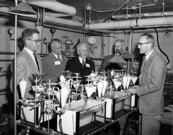 Two Wisconsin daily newspaper editors are shown as they tour the U.W. Lake Laboratory. Will Conrad, <I>Medford Star News</I> editor, and Charles E. Broughton, <I>Sheboygan Press</I> editor, listen to Professors William B. Sarles and Arthur B. Hasler of the U.W. Zoology Department talking about fish and lake water.