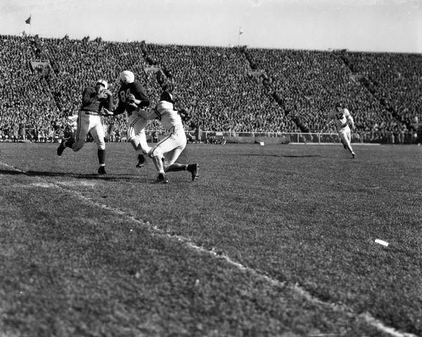 Roy "Colonel" Burks catches a pass from quarterback John Coatta in front of end Tilden Meyers (#84) during the football game between Wisconsin and Purdue at Camp Randall Stadium. Purdue's Neil Schmidt (#40) defends.