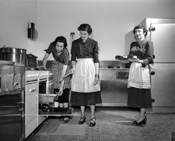 Three women working in the kitchen of the newly-completed Temple Beth El on Arbor Drive. Three chairmen of the upcoming bazaar are, left to right: Mrs. Harry (Flavina) Heilprin, 4128 Hiawatha Drive; Mrs. (Harriet) Spector, 3918 Shawnee; and Mrs. Vera Schwid, 1015 Oak Way.
