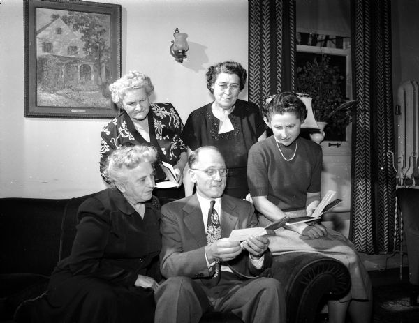 Sydney S. Miller, manager of the Madison Social Security Office, shares a 1950 government-issued booklet explaining a program to employers of household workers who will be brought into the system at the start of the next year, to members of the Woman's Club who will aid in the distribution of the booklet. The women in the picture are (left to right): Mrs. W.D. Laura Mack, Mrs. Everett W. (Frances) Rowe, Mrs. George L. (Edna) Joachim, and Mrs. J.E. (Marion) Goetz.