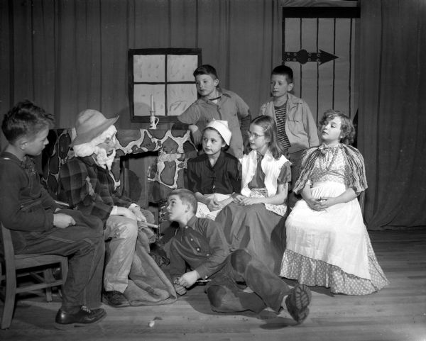 A scene from the Lapham School fifth grade production of Johnny Appleseed.  Actors, left to right: Dennis Crary, Bob Alcumbrac (as Johnny), Anne Marie Teegardin, Gladys Decker, and Nancy Glidden. Bill Mueller, sitting on the floor.  Standing are Don Jensen and Keith Hewitt.