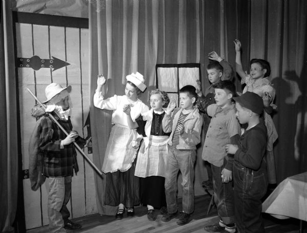 A scene from the Lapham School fifth grade production of Johnny Appleseed. Waving goodbye to Johnny (Bob Alcumbrac) are left to right:  Rosemary Reding, Louise Hehn, Keith Hewitt, Don Jensen, Dennis Crary, and in the rear, Bill Mueller, and Nancy Hustad.