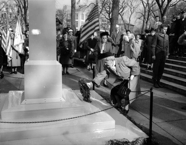 Mrs. Minnie Wiese of 317 West Washington Avenue, representing the Grand Army of the Republic, places a wreath at the base of the cenotaph at the Armistice Day Ceremony at Capitol Square.
