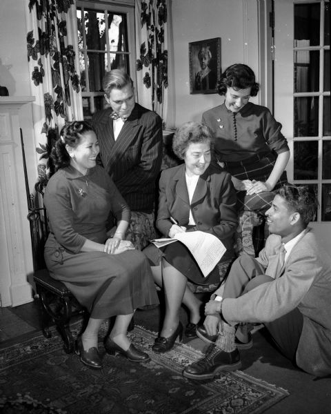 Mrs. Arnold S. (Laura) Jackson confers with four young people about plans for the entertainment of foreign students in the homes of Madison families on Thanksgiving Day. Surrounding Mrs. Jackson (left to right) are: Jesusa Concha of Manila, Philippines, a University of Wisconsin pharmacy student; John Hilgendorf, Stevens Point, vice-president of the university YMCA; Mary Moore, a YWCA member; and Jai Trivedy, India, a University of Wisconsin dairy husbandry student.