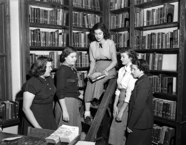 Five members of the Edgewood library club who will attend the Wisconsin Catholic Library Association meeting at Milwaukee Pius XI high school posing for a group portrait in a library. From left are Betty Jane Matts, Wanda Esser, Margaret Sweet, Patricia Whalen, and Rita Burger.