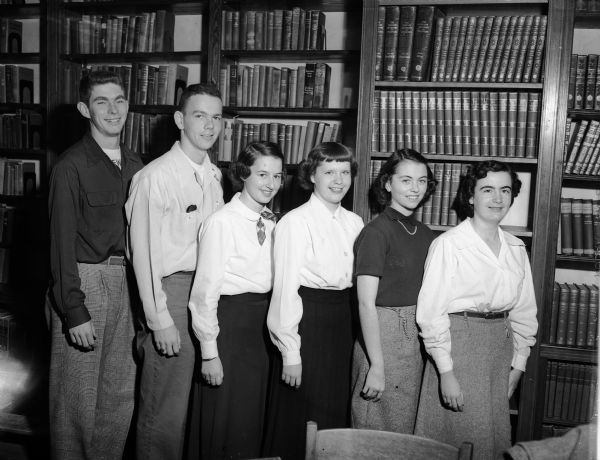 Six Edgewood High School seniors who represented their school at a symposium at St. John's Catholic high school in Milwaukee posing for a portrait in a library. From left are Leroy Berigan, Kenneth McCormick, JoAnne Handel, Peggy O'Neill, Jeanne Tierney, and Joanne Hand.