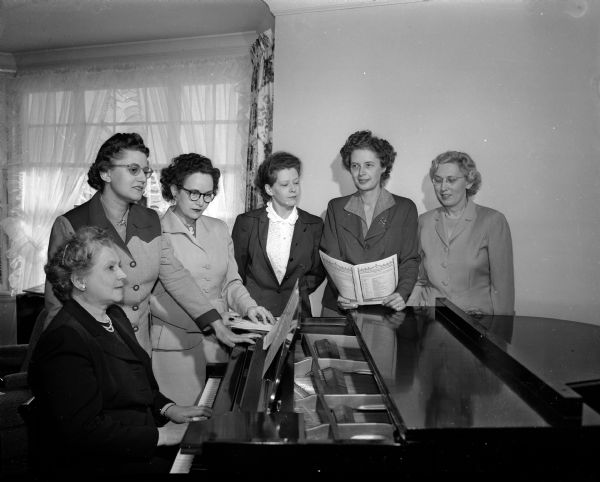 Alumnae of Sigma Alpha Iota music sorority, members of the arrangements committee for the Founder's day twilight musicale, gather around a piano for a group portrait. Pictured, from left, are Mrs. F.I. (Henrietta) Schmidt (seated), Mrs. W. G. (Lois) Dennis, Mrs. H.J. (Monona) Schantz, Mrs. M.W. Bessert, Mrs. Carl H. (Katherine) Engler, and Mrs. J.A. (Josephine) Fitschen.