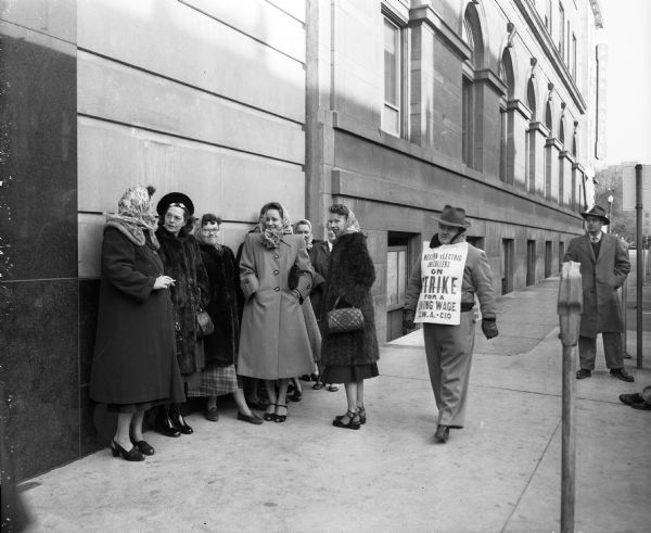 A group of Western Electric workers picket the Wisconsin Telephone Exchange at 122 West Main Street off the Capitol Square in Madison. The Park Hotel sign can be seen on the far corner.