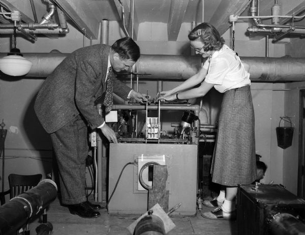 University of Wisconsin professor J.W. Williams, and Mrs. Winifred Saunders, research associate, work with an electrophoresis instrument in a laboratory in the chemistry building. The instrument is used in tuberculosis research.
