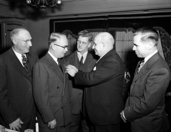Arthur F. Trebilcock, president of the Kennedy-Mansfield division of Borden's, receiving his pin and certificate of membership in the company's Quarter Century Club from Jay A. Murrey, the oldest member in point of service (37 years). Looking on, left to right, are: Manley R. Showers, Jr., Andrew S. Madsen, and Albert W. Baer, all who were also initiated into the club.