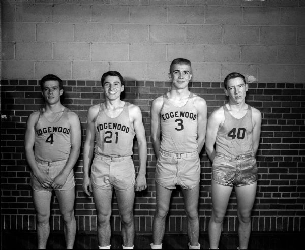 Four players of the Edgewood boy's basketball team, 1950-51 season, posing against a brick wall for a portrait. They are #4 Edward McNamara; #21 Jerry Higgins; #3 Tom Haen; and #40 Ken Corcoran.