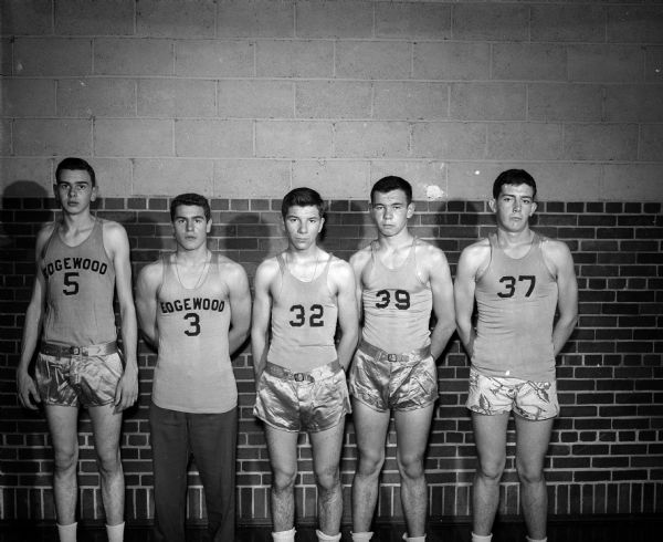 Five players of the Edgewood boy's basketball team, 1950-51 season, posing against a brick wall for a portrait. They are #5 Don Collins; #3 Tom Haen and three unnamed players wearing #s 32, 39 and 37.