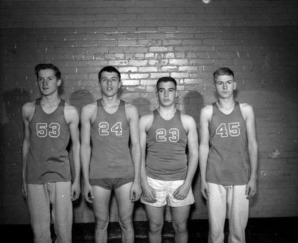 Four members of the Wisconsin High School basketball team, in uniform, posing for a group portrait. They are, left to right: Richard, Koch, Mike Woldenber, Richard Edward, and Jack Burkhalter.