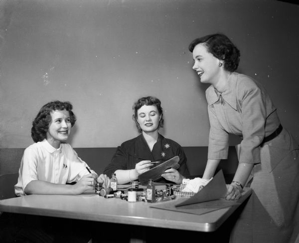 Three members of the Dames Club, a group for wives of University of Wisconsin students, work on the Santa Claus program for the annual Christmas party. From left are: Mrs. Miles Meunier, Mrs. Harold Bell, and Mrs. Gordon Wood.