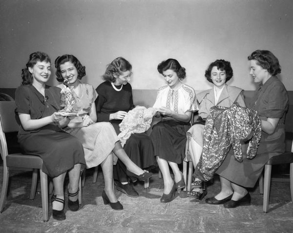 Six members of the Dames Club, a group for wives of University of Wisconsin students who are from foreign countries, gather to do what appears to be craft work. From left are: Mrs. Francisco Marcham, Puerto Rico; Mrs. Alfred Menendez, Colombia; Mrs. John Woodard, South Africa; Mrs. Miodrag Georgevich, Yugoslavia; Mrs. Talha Yaffi, Lebanon; and Mrs. Joseph Hirschberg, France.