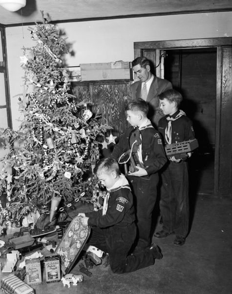Cub Scouts from Pack 304 place toys for less fortunate boys and girls under a Christmas tree at St. Mark's Lutheran Church. The toys will go to the Wisconsin State Journal's Empty Stocking Fund. From left are: Robert Irvine, Robert Hilliard, Jackie Olson, and pack committeeman Gordon Hilliard.