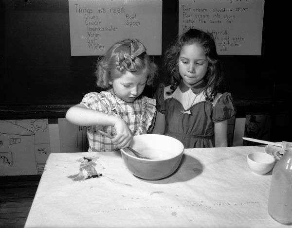 Second grade children of Lowell School engaging in a class project of making butter as part of a dairy study. Karen Rockney (left) is washing the butter as Patricia Corona is looking on.