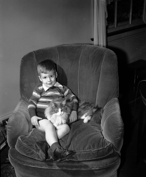 Douglas Shaw Woodman, age 3, sitting with his Persian cat, "Mr. Thomas."