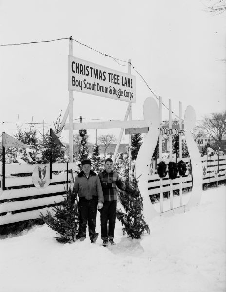 Charles Amacker, left, and Kenneth Greve, members of the Four Lakes Drum and Bugle Corps, stand in front of the Corps' Christmas tree lot located in the 1100 block of East Washington Avenue.