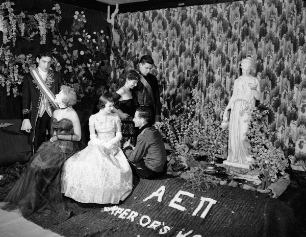 A scene from the "Emperor's Waltz" party at the Alpha Epsilon Pi Fraternity house. In the library decorated as a formal garden are, seated, left to right: Marilyn Fein, Auburndale, Massachusetts; Rosalie Alschuler, Aurora, Illinois; and Bernard Goldstin, Atlanta City, New Jersey. Standing are: Alvin Reiss, New York City; Peggy Woldman, Milwaukee; and Jerry Finegold, Madison.