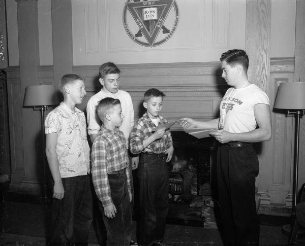 Receiving a diploma for attending the Basketball Clinic from YMCA physical education director Don Brault are: Carl Tyggrum, Bob Coltern, Bob Baker, and an unidentified boy.