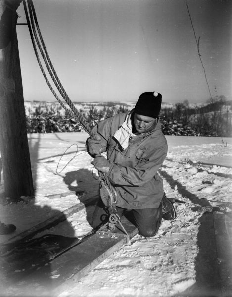 A man prepares to hoist a plank into place during construction of the Blackhawk Ski Club ski jump in anticipation for the second annual jumping meet at Tomahawk Ridge.