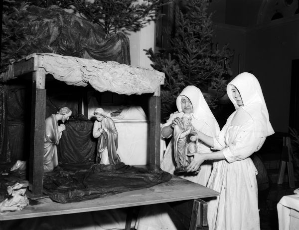 Two Christian nuns, Sisters Mary Gile and Mary Louise, are shown setting up the Nativity crib for the Christmas tableau in the Sisters' chapel at St. Mary's Hospital.