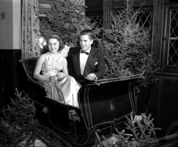 Marita Schumpert and Toby Reynolds, two of the people who helped make arrangements for the University Club Christmas Dance, sit in a sleigh at the party.