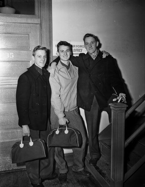 Three brothers, part of the thirty-three enlistees accepted by the Madison Air Force recruiting station, posing near the office in the Federal building. The three Madison brothers are twins Duane (left), and Don (right) Van Haren with their brother, Jack, in the center.