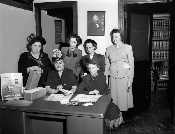 Members of the Madison Business and Professional Women's Club address envelopes to be sent out for the March of Dimes fundraising campaign.  Seated, left to right, are: Mrs. Charles E. Hemingway, club president; and Edna Rengstorff, club treasurer. Standing, left to right, are: Anita Scheibel, club secretary; Faye Robbins, corresponding secretary; Ardis Kirkpatrick, membership chairman; and Gertrude (Mrs. Ernest H.) Anderson, club vice-president.
