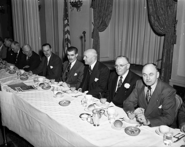 Men sitting at the speaker's table at the annual Security State Bank dinner at the Hotel Loraine for the East Side Business Men's Association. Seated right to left: unidentified man, Marvin E. Smithback, president of ESBMA (wearing boutonniere); L.L. Lunenschloss, president of the bank; Don Anderson, publisher of the Wisconsin State Journal; Thomas E. Coleman, Security State Bank director; F. Halsey Kraege, president of the Madison and Wisconsin Foundation.