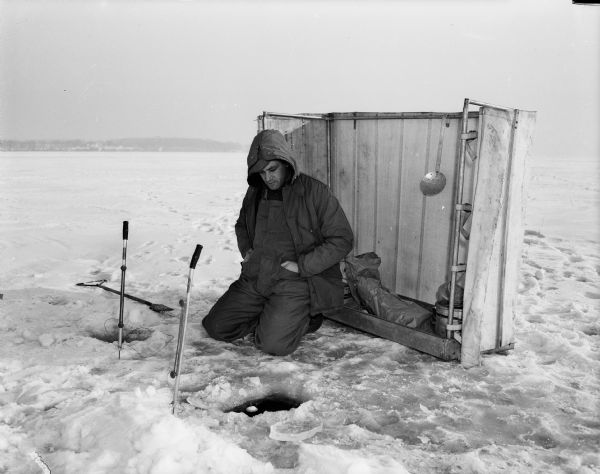 Glen Dickerson of Sauk City ice fishes on Lake Mendota while sitting in front of a windbreak made of a grain binder apron.