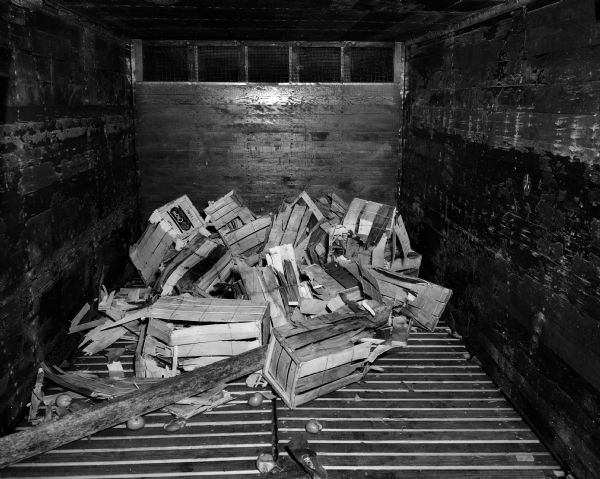 Interior view of a wooden Illinois Central Railroad car containing damaged orange crates.