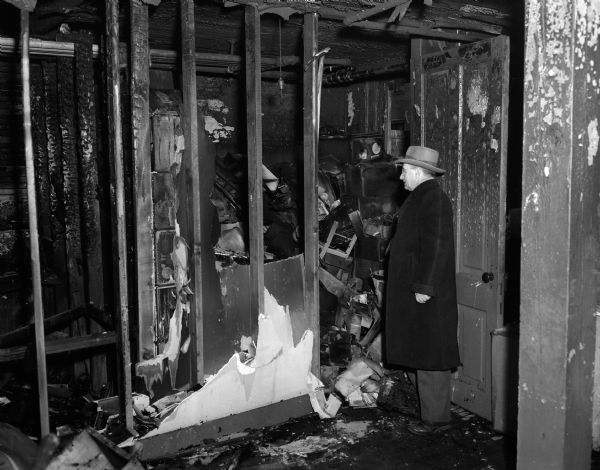 Major Ira E. Nolte, Madison district commander of the Volunteers of America, inspects the wreckage left by a fire which destroyed two basement supply rooms and damaged the chapel at the organization's building at 412 South Baldwin Street.