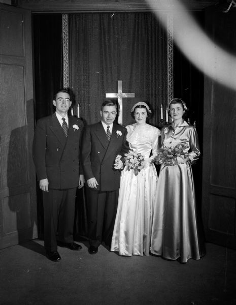 Group portrait of the Salk-Lange wedding party in front of the altar at Bethel Lutheran Church. Left to right: Best man Harvey Lange, St. Louis, Missouri, brother of the groom; Eugene Albert Lange, groom; Lois Schoman Salk Lange, bride, and Mrs. J. Deane C. Gannon, sister of the bride and matron of honor.