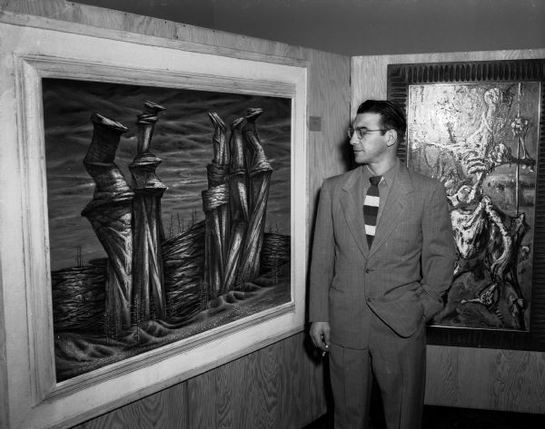 Santos Zingale of the University of Wisconsin art department faculty stands beside his painting, "Variations on a Theme", which won the $100 Award of Excellence in the Madison Artist' Show. The show was sponsored by the Madison Art Association.