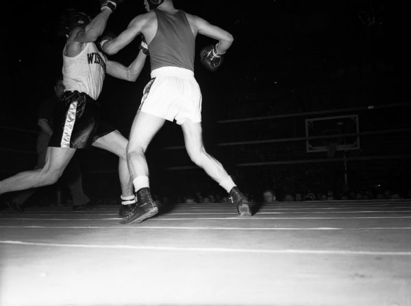 Action photo of a boxing match between the University of Wisconsin and Syracuse University at the University of Wisconsin-Madison Field House.