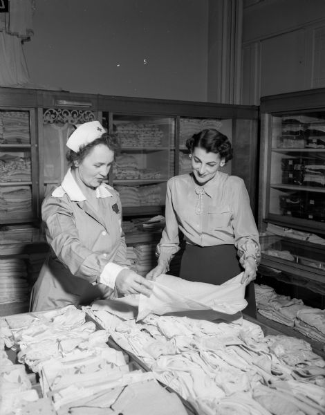 Uniformed Siri Anderson, a Red Cross Gray Lady, purchases lingerie for a patient from Olga Meszatos at the Emporium Department Store.