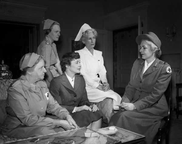 Blood collection volunteers are instructed by Elizabeth Bell, right, chair of Red Cross volunteer services. Seated, left to right: Rosa Fred, canteen worker and wife of the University of Wisconsin President, Edwin B. Fred; Charlotte Kohler, staff aide and wife of Governor Walter J. Kohler, Jr.; and Melba Neupert, registered nurse and wife of the state health officer. Standing: Helen Giessel, canteen worker and wife of the state budget director.