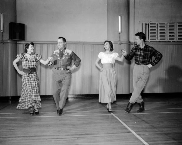 Two couples, co-chairmen of the upcoming state-wide jamboree of the Square Dance Association of Wisconsin, demonstrate a square dance step. They are, from left: Mr. and Mrs. Herbert Johnson, and Audrey Helmke and Rollie Endres.